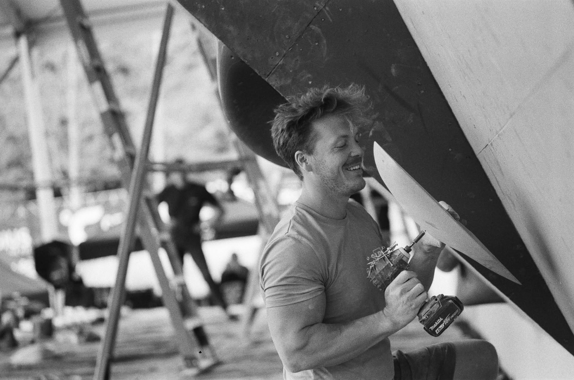 Cody Grodzki routesetting with a drill at a competition wall